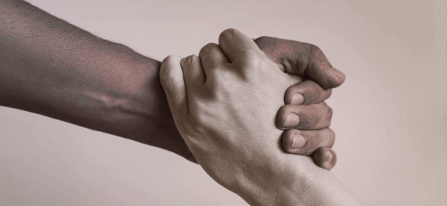 Two different people's hands grasping each other helping